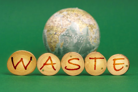 Ecological concept. On a green background there is an Earth globe and wooden roundels with the inscription - Wasteの写真素材