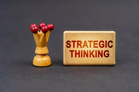 Leader concept. On a black surface there is a chess piece and a wooden block with the inscription - Strategic thinkingの写真素材