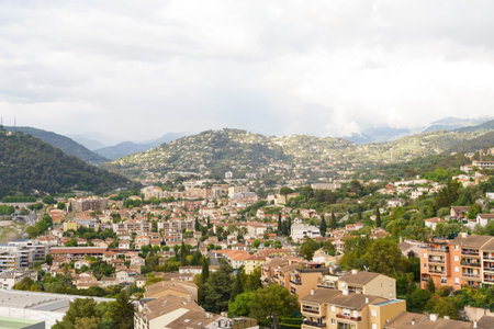 A city nestled at the foothills of towering mountains, creating a striking contrast between urban structures and natural beauty.の写真素材