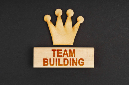 Leader concept. On a black surface there is a wooden crown and a block with the inscription - Team buildingの写真素材