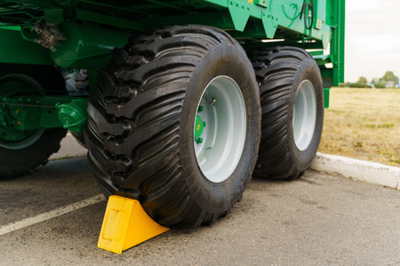 A green dump truck is parked in a parking lot, surrounded by other vehicles. The truck is large and...