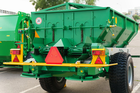 A green dump truck is parked in a busy parking lot, surrounded by other vehicles and pedestrians.