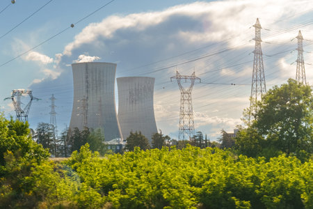 A nuclear power plant stands tall in the middle of a vast field, surrounded by greenery and under a...