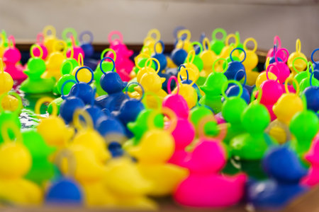 Plastic multi-colored toy ducks float in the water. Children's game of catching ducks with a hook