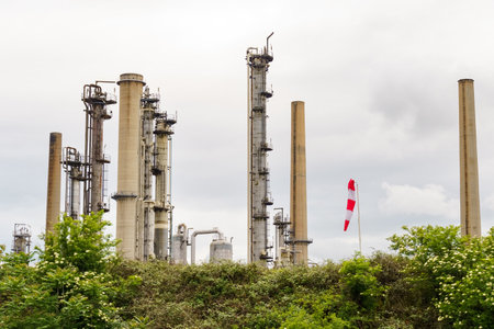 A row of tall, disused industrial smokestacks stands against a cloudy sky, remnants of a bygone...