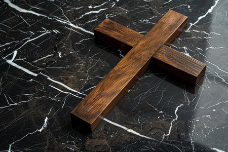 A wooden cross resting on top of sleek black marble flooring.の素材