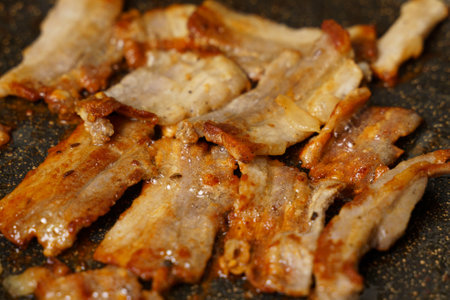 A detailed view of raw meat sizzling and searing on a hot cooking pan, with visible grill marks forming.の写真素材