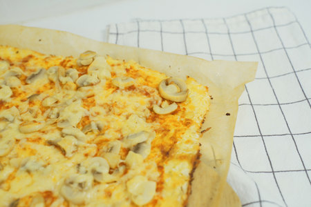 A detailed view of a freshly baked pizza topped with sliced mushrooms, showing its golden crust and savory toppings.の写真素材