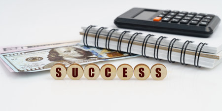 Business and finance concept. On a high surface lie a notepad, a calculator, dollars and wooden...