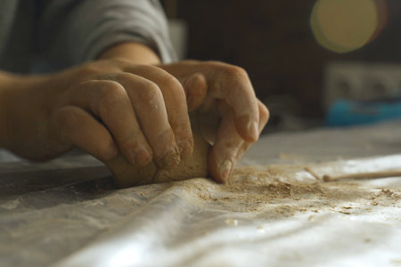 Women's hands knead dense clay for working on a potter's wheel. Making crafts from clay. Hobbies and...
