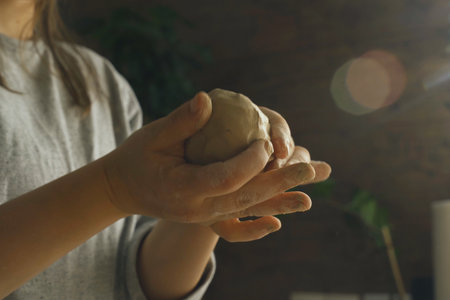 Women's hands knead and beat a clay ball to make ceramic products. Close-up. Creative hobby.