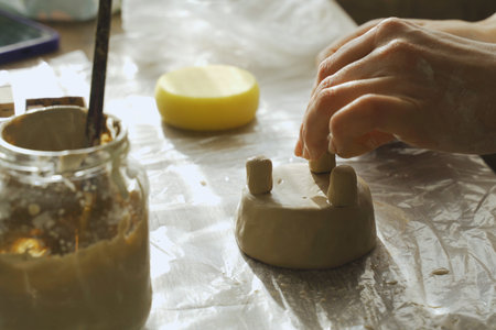 A woman makes a ceramic pot and attaches the legs. Close-up. Creative hobby.