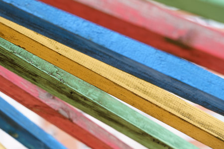 A group of multicolored wooden boards stacked on top of each other, creating a vibrant visual...