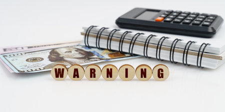 Business and finance concept. On a high surface lie a notepad, a calculator, dollars and wooden...