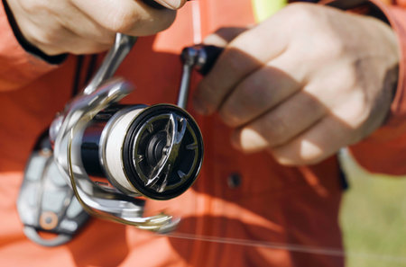 A close-up of a persons hands holding a fishing rod with a reel attached, ready for fishing.の写真素材