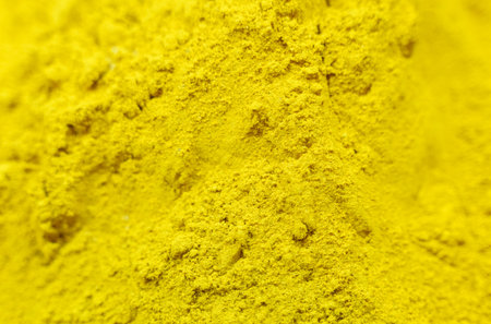 A detailed close-up showcasing the fine texture of vibrant turmeric powder.の写真素材