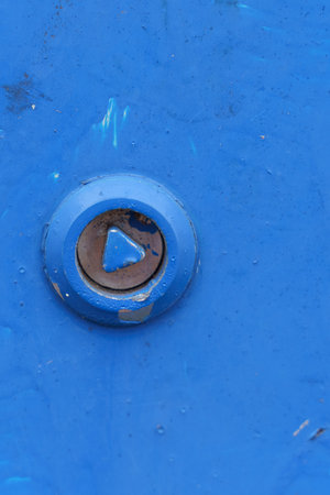 A detailed view showing a rusty bolt embedded in a textured blue metal surface, highlighting the contrast between the worn metal elements and the vibrant blue paint.の写真素材