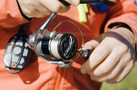 A person standing holding a fishing rod and reel in their hands.の写真素材