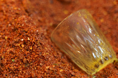A close-up view of a glass nestled within a mound of dirt, showing the contrast between the transparent glass and the earthy soil.の写真素材