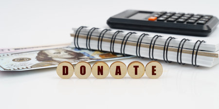 Business and finance concept. On a high surface lie a notepad, a calculator, dollars and wooden...