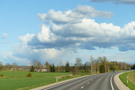 A long road stretches into the distance beneath a sky filled with billowing clouds.の写真素材