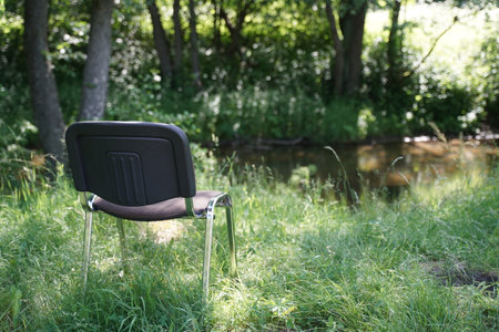 A black chair placed atop a vibrant green field.の写真素材
