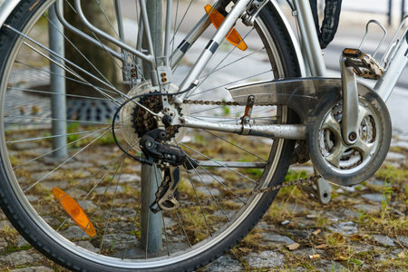 A bicycle is parked on a city sidewalk, leaning on a metal rack. The scene conveys urban...