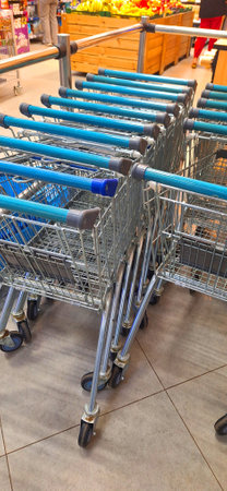 A row of empty shopping carts lined up neatly in a grocery store aisle, ready for customers to use.の写真素材