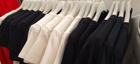 A rack filled with white and black pants hangs neatly on a wall, creating an organized display.の写真素材