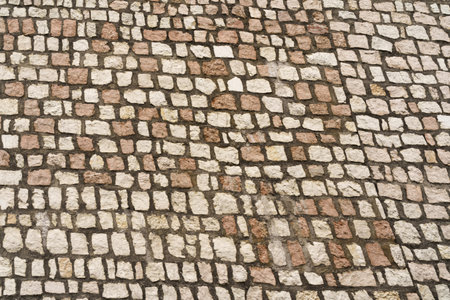 Detailed close-up view of weathered cobblestones forming a street surface with a textured and abstract pattern.の写真素材