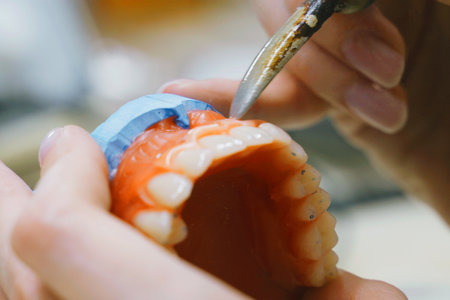 A dental technician uses precision tools to solder and shape dentures, showing expert craftsmanship in dental manufacturing.の写真素材