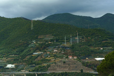 A view of rolling green hills with power lines and a highway bridge in the Italian countryside.の写真素材