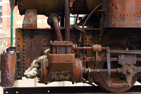 A weathered and rusted steam engine in Astorga, Spain, with a large rock wedged in its machinery,...