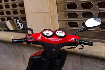 A red scooter with two mirrors parked on the street, reflecting its surroundings.の写真素材