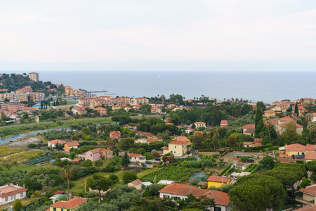 A panoramic view of a charming coastal village in Italy, showcasing vibrant green foliage and colorful houses, all overlooking a sparkling blue sea.の写真素材