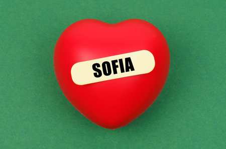 A striking red heart is prominently displayed, bearing the name Sofia, conveying a personal message of love on a vivid green background.の写真素材