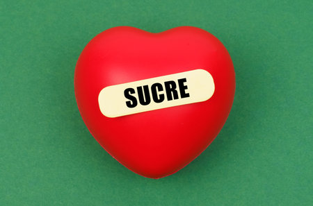 A bright red heart rests on a green backdrop, embodying themes of love and sweetness in a creative display.の写真素材