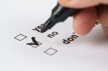 A close-up view of a hand using a black marker to select the answer on a checklist, confidently choosing yes over the other options in a clear decision-making moment.の写真素材
