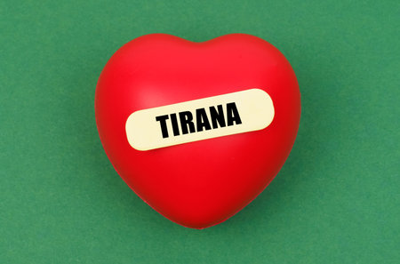 A bold red heart with the name Tirana affixed, radiating affection for the city against a bright green surface.の写真素材