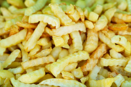 A generous heap of crinkle cut fries fills the frame, showing their crispy texture and golden hue. The scene highlights the irresistible allure of freshly cooked fries in a playful arrangement.の写真素材