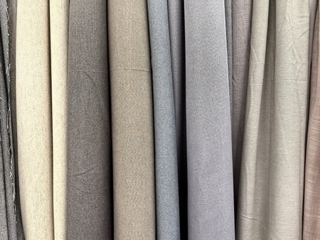 A vibrant display of fabric rolls showcases an array of soft, muted colors and textures. The gentle hues blend harmoniously, inviting inspiration for creative projects.の写真素材