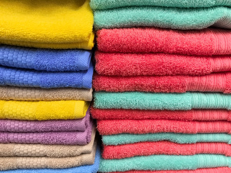Colors blend beautifully as various towels are stacked meticulously, showing a palette of yellows, blues, pinks, and greens. The soft fibers hint at comfort and cleanliness, ideal for any bathroom.の写真素材