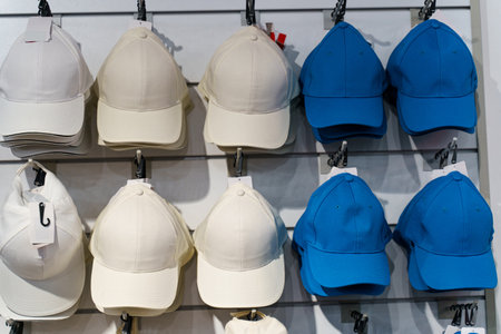 A vibrant array of beige and blue caps hangs neatly on a display wall in a retail space. The caps exhibit simple designs, ideal for casual wear or outdoor activities.の写真素材