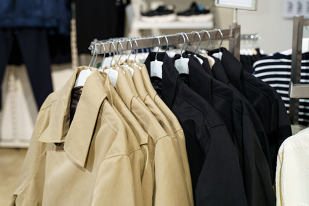 A collection of elegantly designed coats hangs neatly on a metal rack in a modern boutique. The...