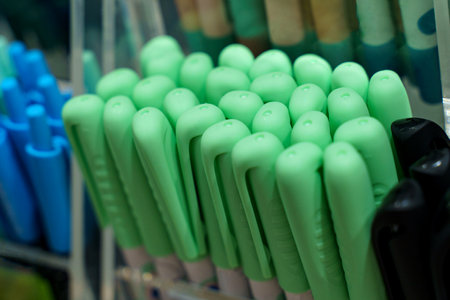Rows of vibrant green pens rest in an organized manner on a display stand. The stationery collection showcases different shades and styles. Bright colors create an inviting atmosphere for shoppers.の写真素材