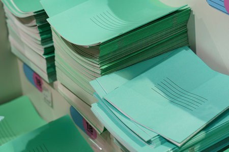 In a vibrant studio filled with natural light, numerous stacks of mint green paper lie in wait, each sheet ready to be transformed into art, notes, or plans by eager hands.の写真素材