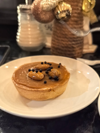 A delightful dessert sits on a white plate, showcasing a smooth caramel filling adorned with roasted...