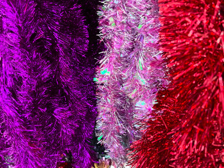 Vibrant tinsel strands in shades of purple, pink, and red hang together, reflecting light in a joyful display. These decorations enhance any party setting, evoking a sense of celebration and fun.の写真素材