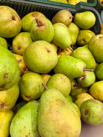 A vibrant display of green pears fills a market stall, showing their smooth skin and fresh appearance. Customers admire the natural beauty and consider selections for their meals.の写真素材