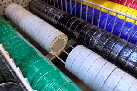 A vibrant assortment of rolls in various colors is neatly arranged on shelves in a crafting supply store aisle. The rolls feature glossy finishes and are ideal for creative projects.の写真素材